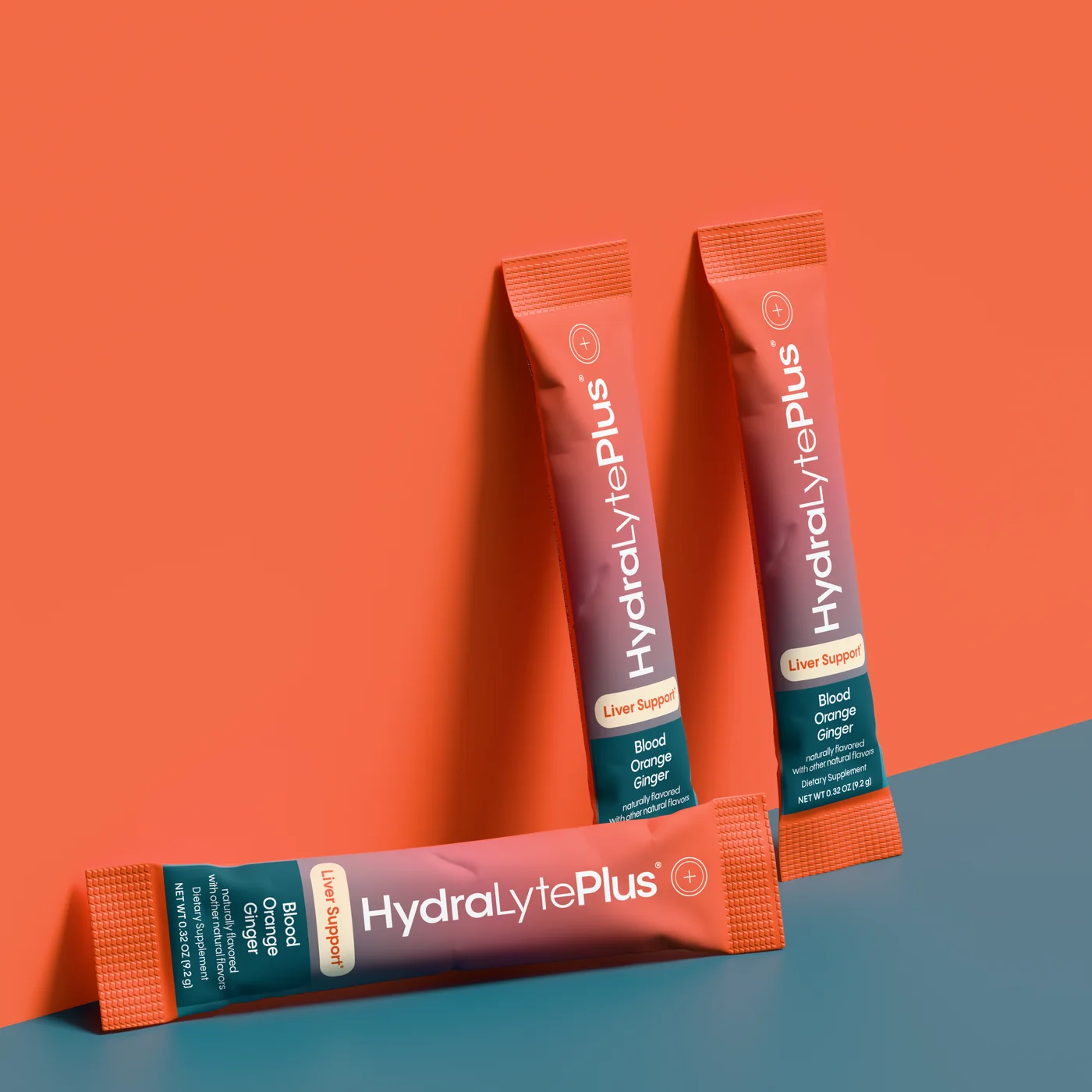Three HydraLytePlus stick packs leaning on a coral wall