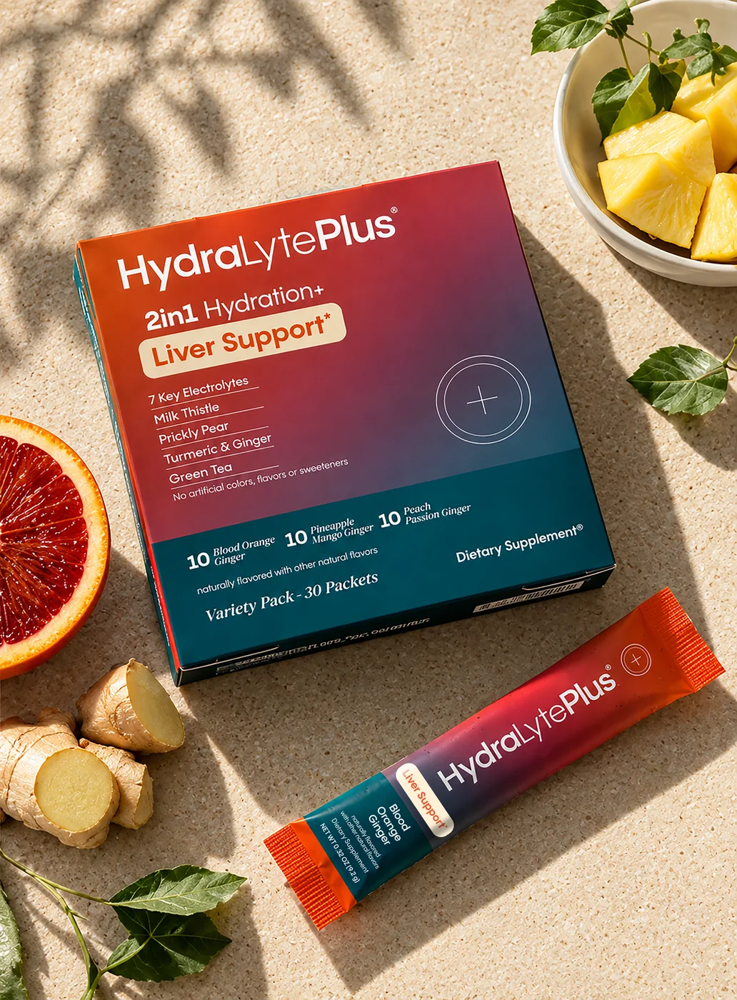 HydraLytePlus carton and stick pack on sand with blood orange, ginger and pineapple